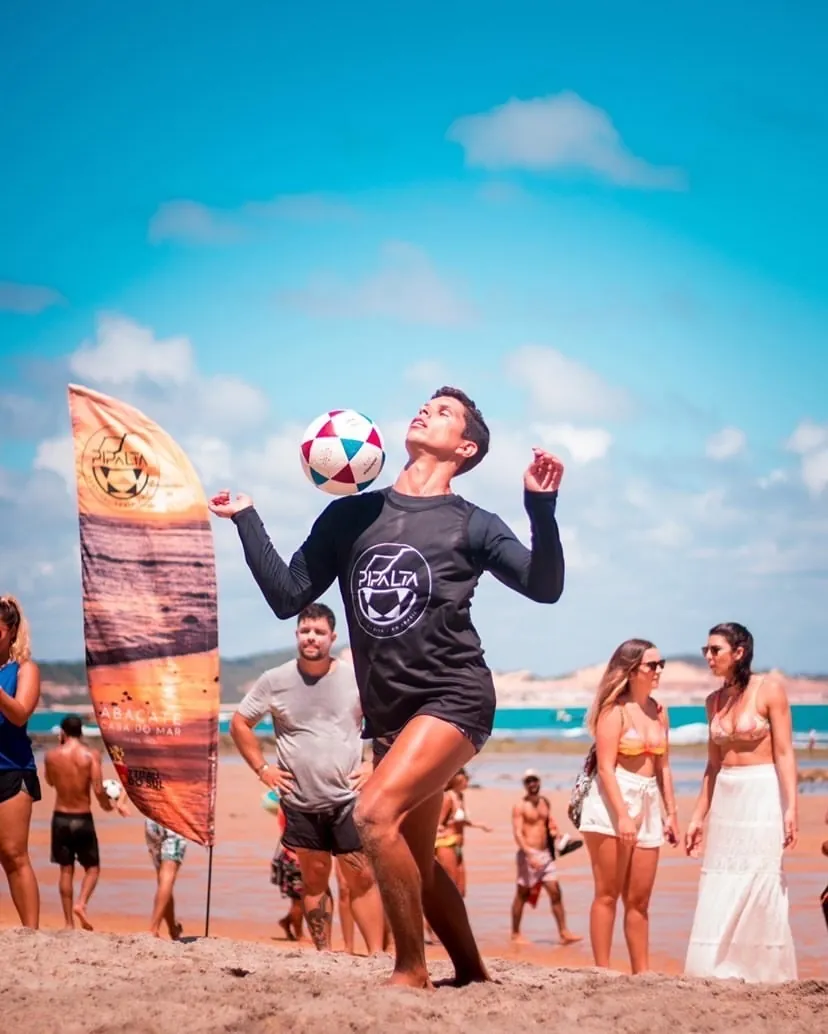 Jogador equilibrando a bola na cabeça na beira do mar