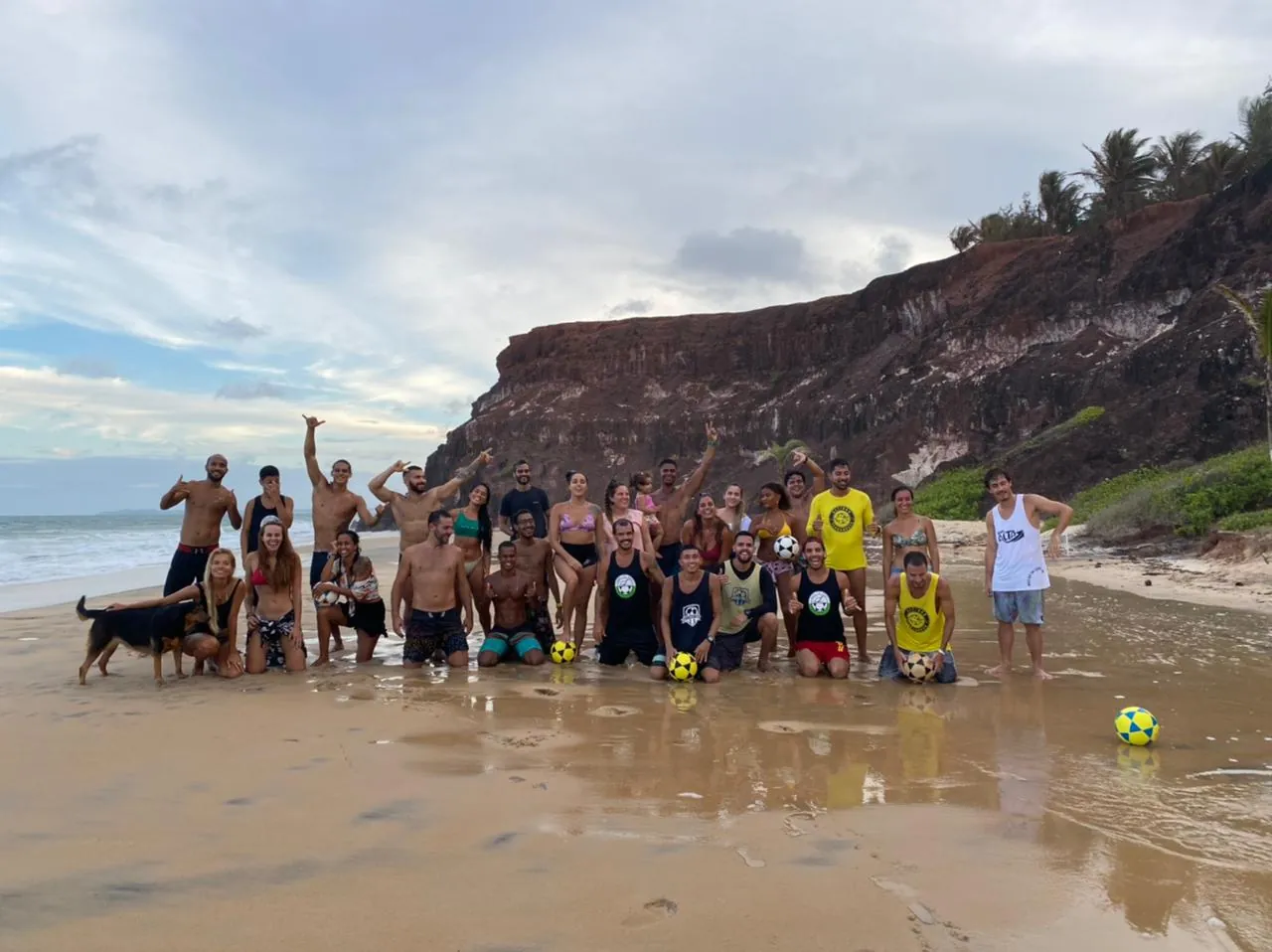 Grupo de alunos reunido na praia com a falésia ao fundo