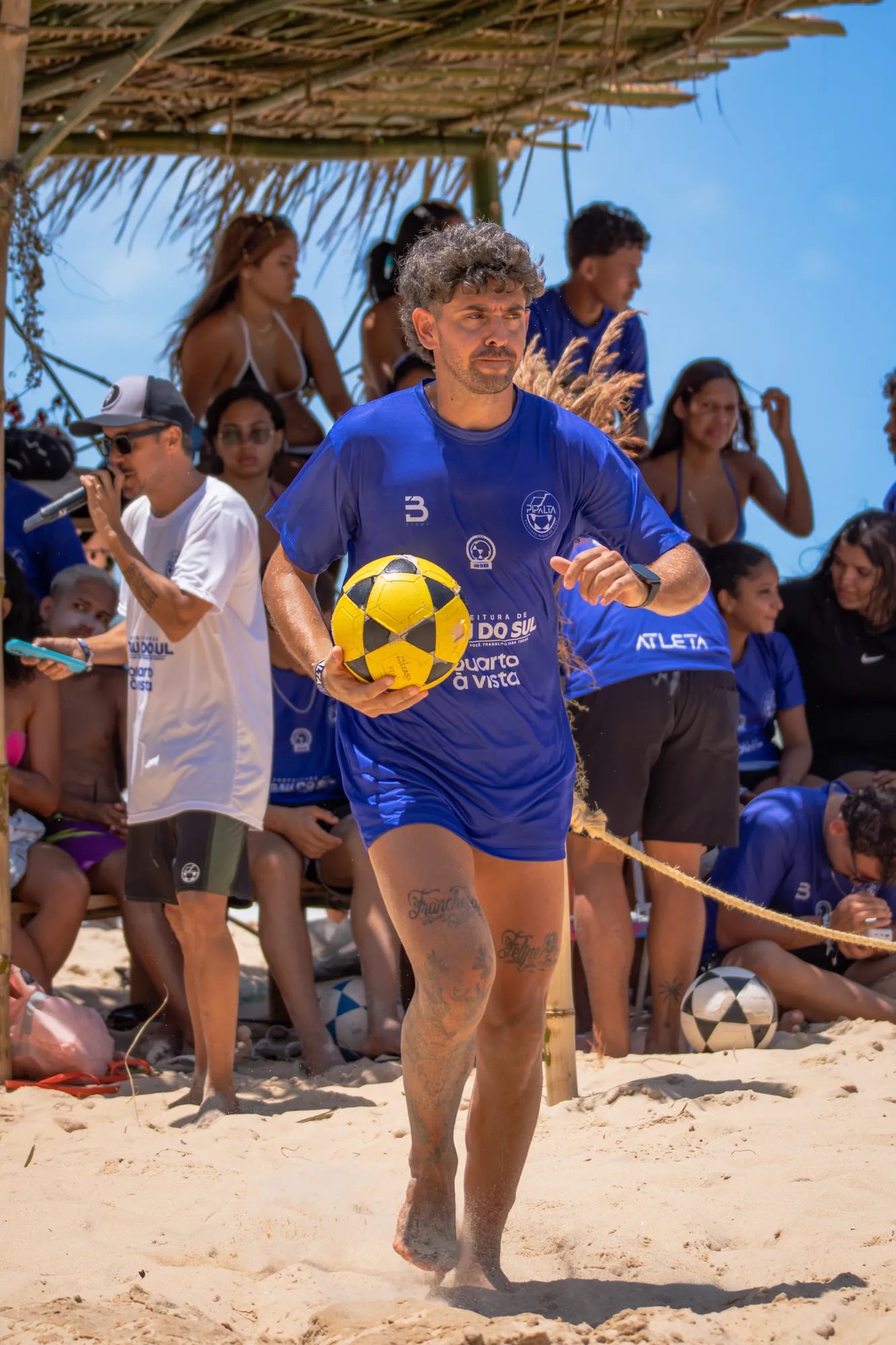 Jogador de camisa azul com a bola na mão na arena