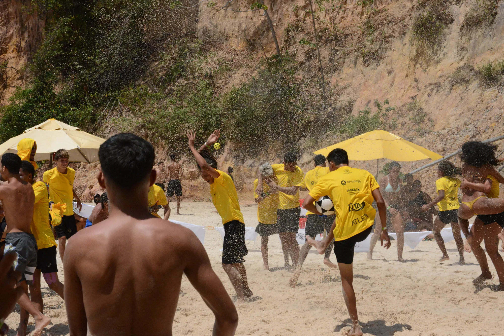 Roda de altinha com jogadores de amarelo e a falésia ao fundo